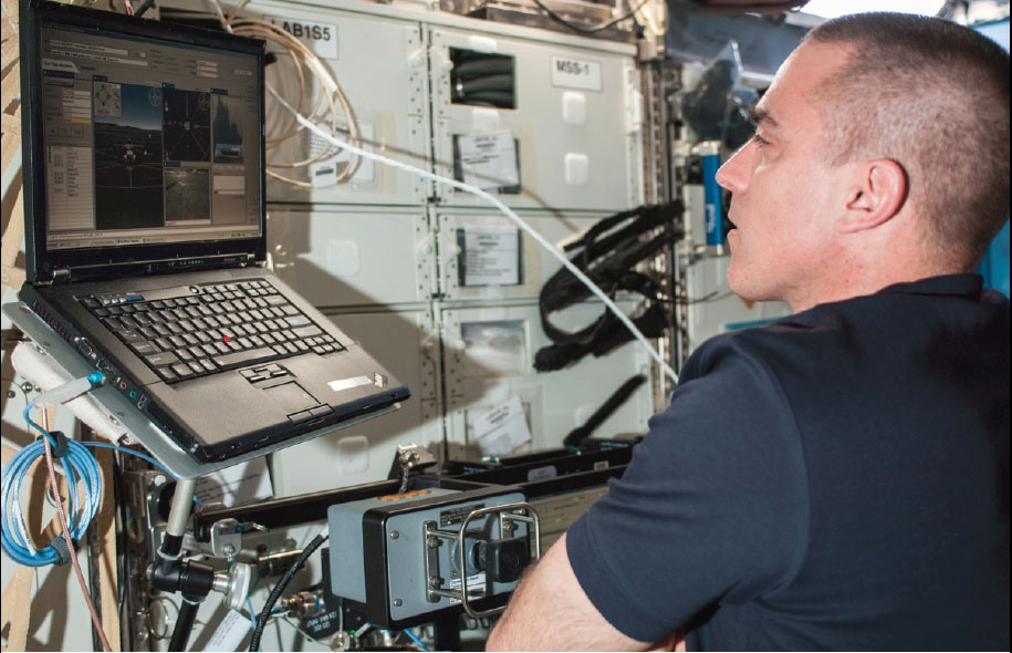 Photo credit: NASA. Chris Cassidy studies the Surface Telerobotics Workbench on the International Space Station to remotely operate the K10 rover on Earth at NASA's Ames Research Center in Moffett Field, Calif., in June 2013.