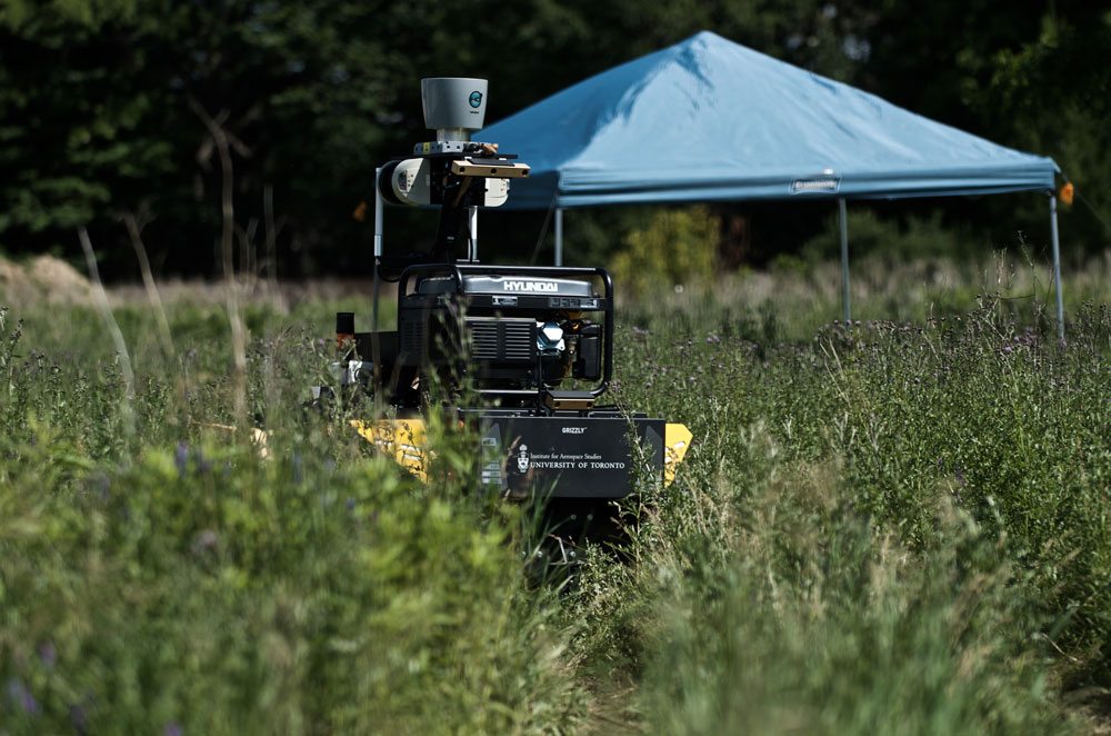  Grizzly RUV crossing dense vegetation and reaching autonomously one of its intermediate goal under the blue gazebo. The robot drove through different types of environments (ex.: indoor, outdoor, road, tall grass) using the same algorithms.  Photo credit: François Pomerleau - University of Toronto.