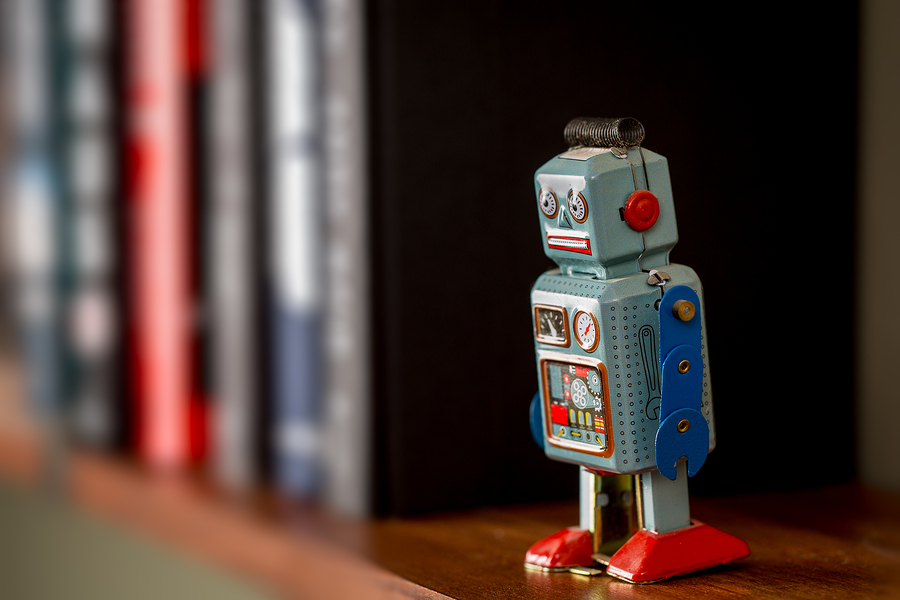 Retro tin toy robot standing on a wooden bookshelf